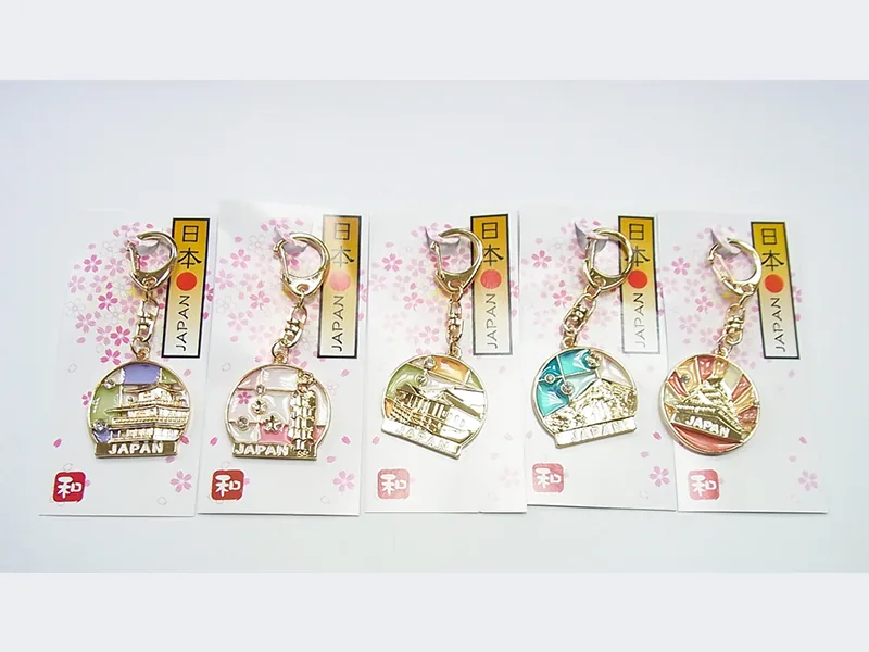 桜と「日本」「JAPAN」の文字が入った台紙に付いた、丸い金具の中に富士山や寺社の風景を収めたキーホルダー5点。金色の枠に「JAPAN」の表示