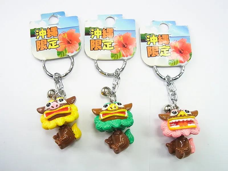 「沖縄限定」の台紙に付いた、花笠をかぶったシーサーのキーホルダー3色。黄・緑・ピンク。鈴が付いている