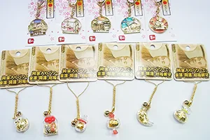 インバウンド向けシリーズの商品を並べた写真。桜柄の台紙に付いた「JAPAN」のキーホルダーと、金色の台紙に付いたお守りストラップ