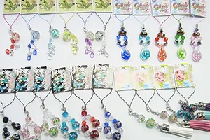 ガラス玉シリーズの商品を並べた写真。透明な玉を連ねたストラップと、花模様の玉にタッセルを合わせたもの