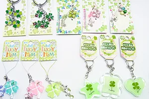 幸せのクローバーシリーズの商品を並べた写真。緑と白で統一された、四つ葉のクローバーのキーホルダーとストラップ